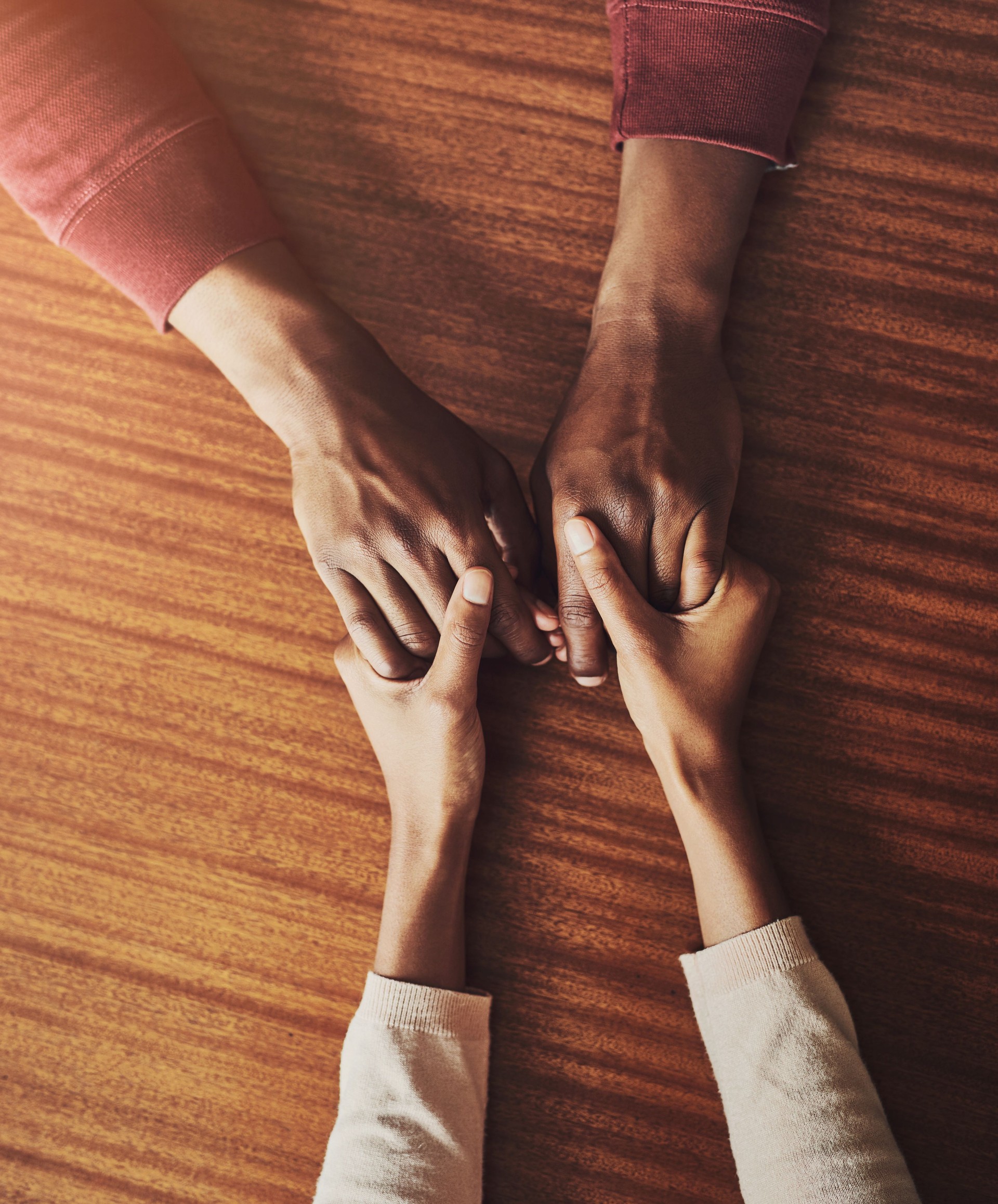 Couple, holding hands and above for support in home for care, connection and empathy for mental health. People, comfort and partner for help with kindness, bonding and solidarity for grief on table